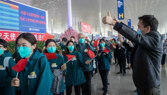 Los voluntarios locales hacen un gesto cuando los miembros del personal médico (en verde) del Hospital de la Universidad de Medicina de Pekín salen del aeropuerto de Tianhe en Wuhan, en la provincia central de Hubei de China, luego de cumplir un largo periodo de trabajo en la ciudad cuna de la pandemia. (Foto: AFP/STR)