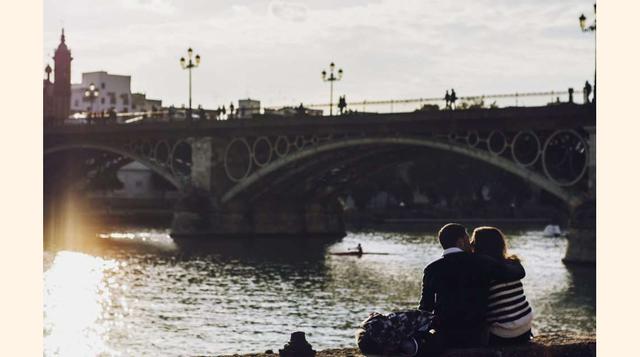 Sevilla (España). Una pareja se besa en la orilla del río Guadalquivir frente al puente de Triana (Sevilla). (Foto: msn)