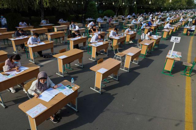 FOTO 1 | Varios estudiantes uzbekos realizan un examen en plena calle en la capital Taskent. (Photo by YURI KORSUNTSEV/AFP via Getty Images)