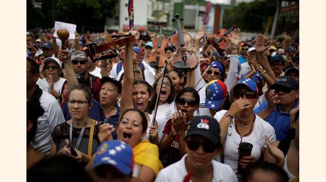 Jóvenes músicos levantan sus violines durante una concentración para rendir homenaje a las víctimas de violencia durante las protestas contra el presidente Nicolás Maduro, el 7 de mayo de 2017, en Caracas.(foto: Marco Bello).