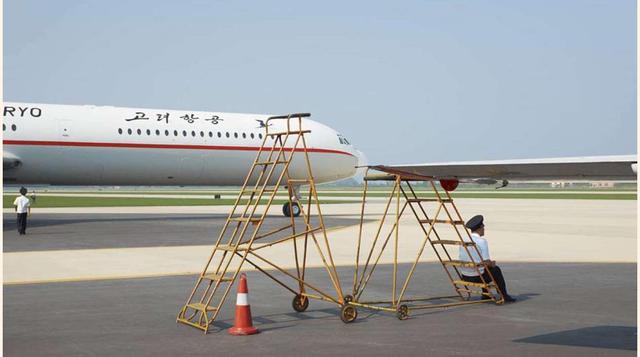 Merecido descanso, un operario descansa en el aeropuerto de Pyongyang con una de las naves de Air Koryo al fondo.