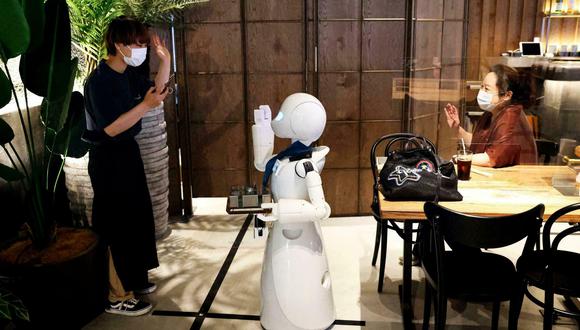 "Hola ¿cómo estás?", dice un brillante robot, que parece un pingüino, desde una barra cercana a la entrada, girando la cara hacia los clientes. (Foto: AFP)