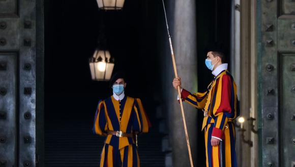 Guardias suizos con mascarillas por el coronavirus montan guardia junto a la Puerta de Bronce en el Vaticano, el 13 de octubre de 2020. (AFP / Andreas SOLARO).