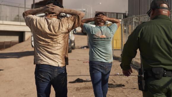 Migrantes detenidos por agentes de la Patrulla Fronteriza de EE. UU., caminan con las manos en la cabeza después de ingresar ilegalmente a los Estados Unidos desde México el 6 de octubre de 2022 en Calexico, California.  (Foto de allison cena / AFP)