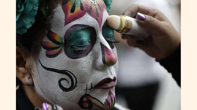 FOTO 9 | Una mujer repasa su maquillaje para convertirse en una Catrina más durante la celebración en Ciudad de México que congrega cada año a miles de personas.