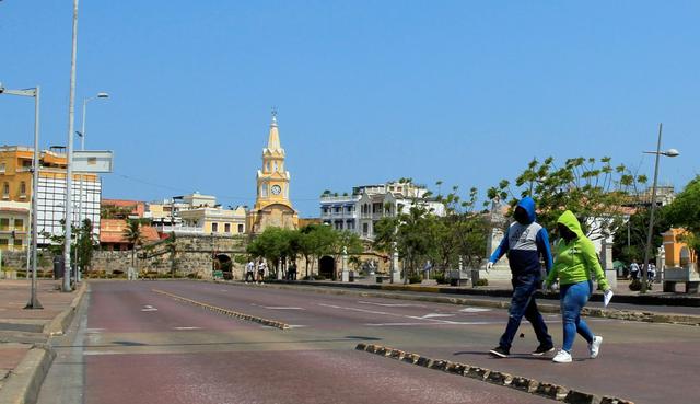 Una pareja totalmente abrigada cruza una calle en Cartagena (Colombia). (EFE/ Ricardo Maldonado Rozo).