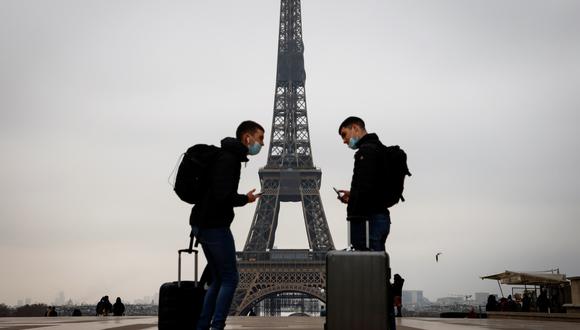 Imagen referencial. Dos jóvenes visitantes cargan sus maletas en la plaza Trocadero con la torre Eiffel al fondo, el 6 de enero de 2021 en París (Francia). (Ludovic MARIN / AFP).