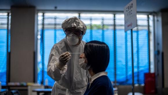 Personal médico  y un funcionario que actúa como paciente realizan una demostración de la prueba PCR para el COVID-19 en un centro en Shinagawa en Tokio, el 8 de mayo de 2020. (Foto de Felipe FONG / AFP)