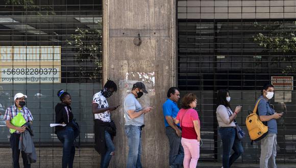 Imagen referencial. Las personas usan máscaras faciales mientras hacen fila para obtener su seguro de desempleo fuera de la sede de la Sociedad de Administración de Fondos de Desempleo en Santiago, Chile (Foto: Martin Bernetti / AFP)