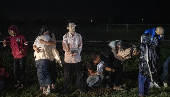Migrantes intentan mantenerse calientes mientras esperan bajo la lluvia después de entregarse a los agentes de la Patrulla Fronteriza de EE. UU. después de cruzar desde México en Frontón, Texas, el 12 de mayo de 2023. (Foto de ANDREW CABALLERO-REYNOLDS / AFP)