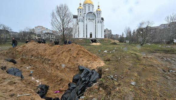 Una fosa común se ve detrás de una iglesia en la ciudad de Bucha, al noroeste de la capital ucraniana, Kiev, el 3 de abril de 2022. (SERGEI SUPINSKY / AFP).