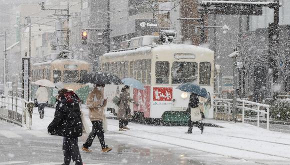 La gente cruza la calle mientras nieva en la ciudad de Toyama, prefectura de Toyama en la costa centro-occidental de Japón, el 24 de enero de 2023, mientras partes del país se preparan para una severa tormenta invernal. (Foto de JIJI Press / AFP)