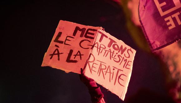 Un hombre sostiene un eslogan que dice en francés "Vamos a jubilarnos del capitalismo" durante una protesta contra la reforma de pensiones del gobierno en Brest, oeste de Francia, el 26 de enero de 2023. (Foto de FRED TANNEAU / AFP)