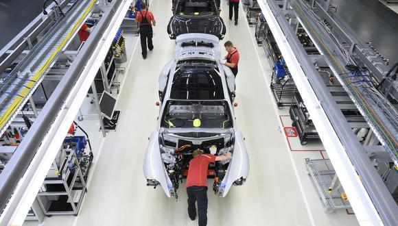 Empleados del productor de automóviles alemán Porsche AG trabajan en los autos deportivos eléctricos Porsche Taycan en la línea de ensamblaje del sitio de producción de Porsche en Stuttgart, suroeste de Alemania, el 26 de septiembre de 2022. (Foto de THOMAS KIENZLE / AFP)