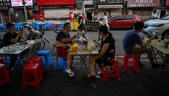 Esta foto del 4 de agosto, 2020, muestra a una pareja comiendo en la tarde al frente de un pequeño restaurante en Wuhan. AFP / Hector RETAMAL