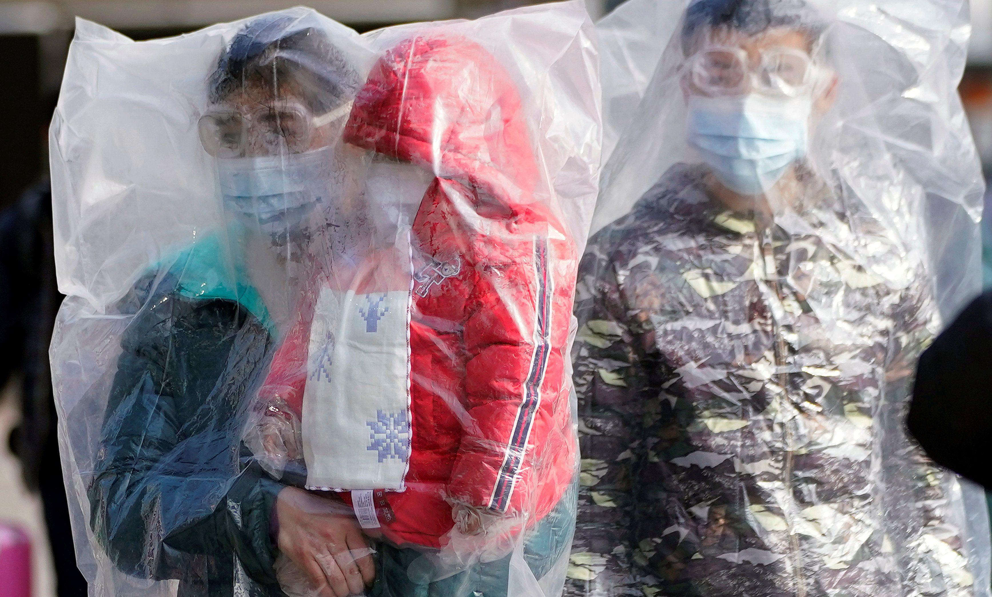 Un grupo de personas que usa máscaras y están cubiertas con bolsas de plástico caminan afuera de la estación de trenes de Shanghai, China, país afectado por el coronavirus. (REUTERS / Aly Song).