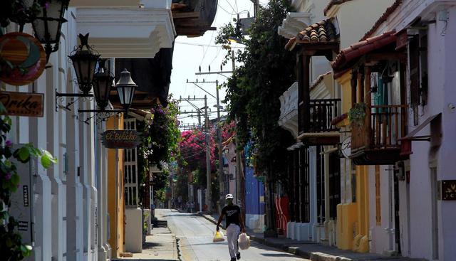 Un hombre carga bolsas con víveres mientras camina por una desolada calle en Cartagena (Colombia). (EFE/ Ricardo Maldonado Rozo).