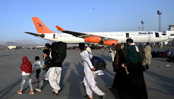 Familias afganas caminan junto a los aviones en el aeropuerto de Kabul en Kabul el 16 de agosto de 2021. (Wakil Kohsar / AFP)
