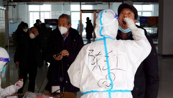 Un trabajador médico con traje protector toma una muestra de hisopo de un hombre para realizar pruebas de ácido nucleico en un complejo residencial, durante otra ronda de pruebas masivas tras el brote del coronavirus en Xian, China. (Foto: cns via REUTERS).