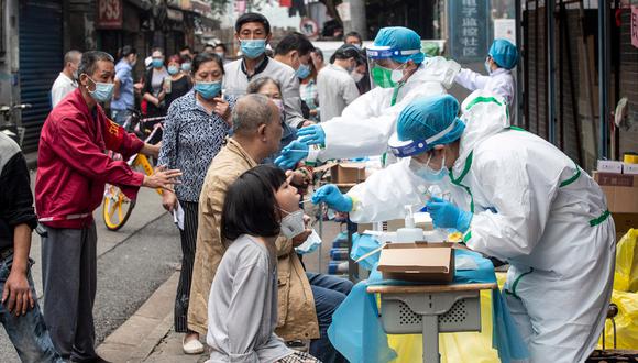 Los trabajadores médicos toman muestras de hisopos de los residentes para analizar el coronavirus COVID-19, en una calle de Wuhan. (Foto: AFP/STR)
