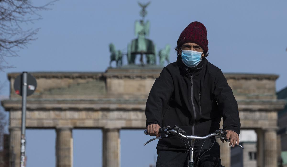 Un hombre con una máscara facial se desplaza frente a la Puerta de Brandenburgo en Berlín, en medio de la pandemia de coronavirus Covid-19. (Foto: AFP/John MACDOUGALL)