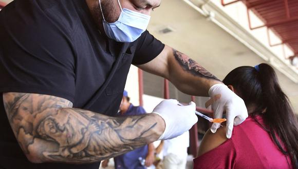 La vacuna Pfizer COVID-19 es administrada por el terapeuta respiratorio Robert Blas (izquierda) en un vecindario del este de Los Ángeles (Estados Unidos), el 9 de julio de 2021. (Frederic J. BROWN / AFP).