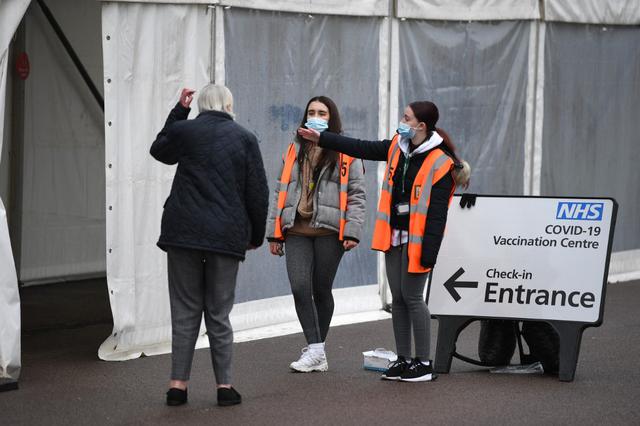Volunteers guide people to a makeshift COVID-19 vaccination center set up at Colchester Community Stadium in Colchester, Essex, southeastern England.  (Daniel Leal-Olivas / AFP)