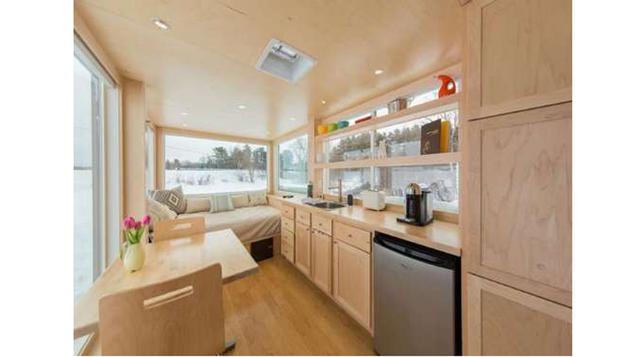 El interior cuenta con una sala de estar, cocina compacta y un baño con ducha, todas ellas decoradas en tonos pálidos.