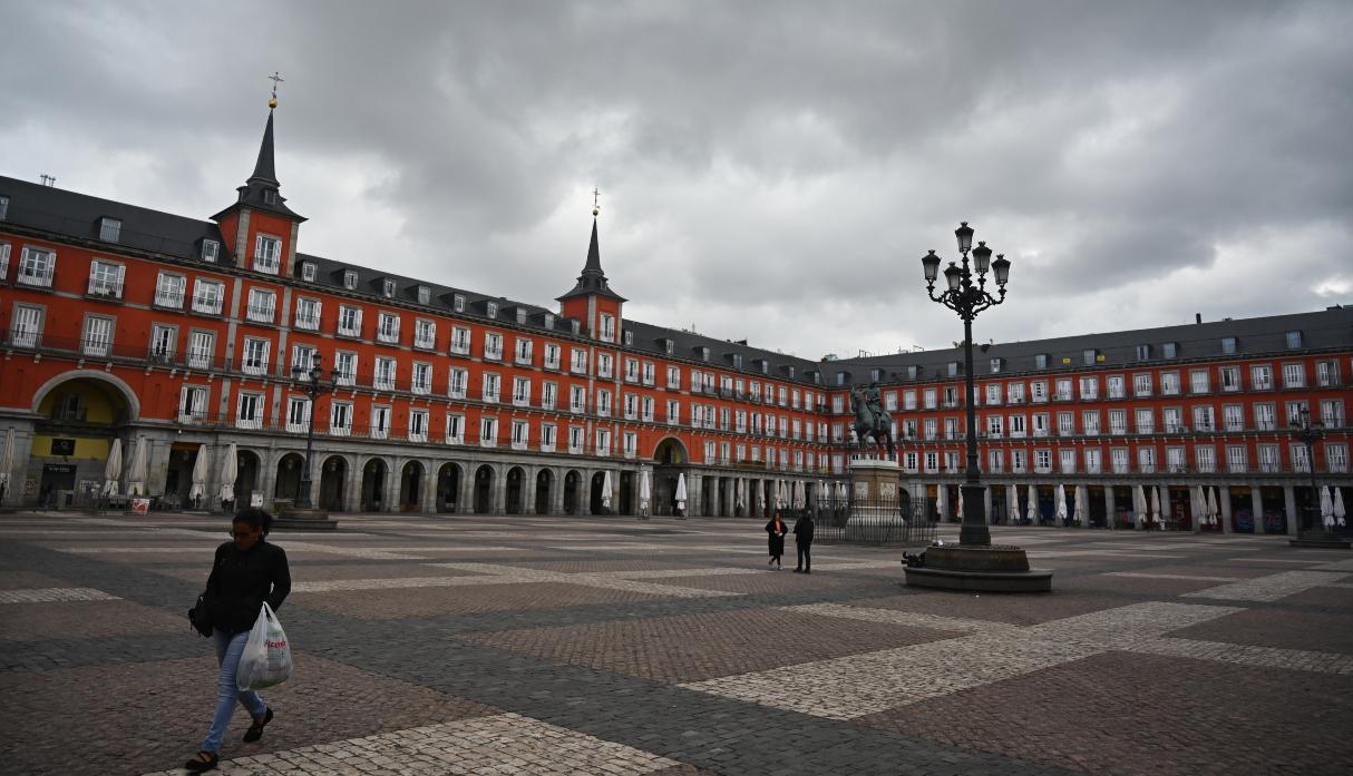 Una mujer es vista llevando bolsas de supermercado por la Plaza Mayor en el centro de Madrid. (Foto: AFP).