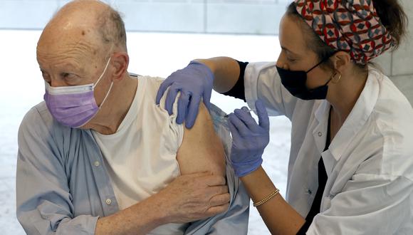 Un anciano mira hacia otro lado mientras se vacuna contra el coronavirus COVID-19 en los Servicios de Salud Maccabi, en la ciudad costera israelí de Herzliya, al norte de Tel Aviv, el 21 de diciembre de 2020. (JACK GUEZ / AFP).