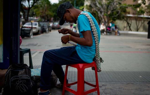 FOTO 1 | 1. El vendedor Wilmer Rojas (25) decidió incursionar en el arte callejero. Comenzó realizando pequeños barcos con los billetes que se encontraba tirados en el piso de las principales avenidas. En 2017, la inflación llegó hasta un 2.600% en Venezuela.  (Foto: AFP)