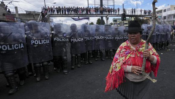Una mujer se para frente a una línea de policías antidisturbios durante las protestas antigubernamentales convocadas principalmente por organizaciones indígenas, en Quito, Ecuador, el jueves 16 de junio de 2022. (AP Foto/Dolores Ochoa).