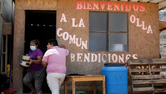 Una mujer sale de una olla común mientras un joven espera su turno en Pamplona Alta, un vecindario de bajos ingresos a las afueras de Lima, Perú. 11 abril 2022. REUTERS/Daniel Becerril