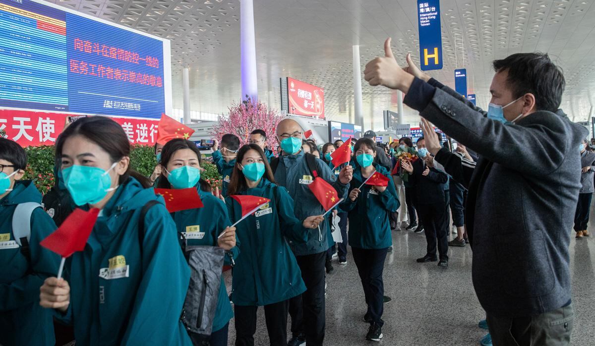 Los voluntarios locales hacen un gesto cuando los miembros del personal médico (en verde) del Hospital de la Universidad de Medicina de Pekín salen del aeropuerto de Tianhe en Wuhan, en la provincia central de Hubei de China, luego de cumplir un largo periodo de trabajo en la ciudad cuna de la pandemia. (Foto: AFP/STR)