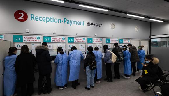 Los trabajadores de la salud ayudan a los viajeros que llegan de China dentro de un centro de pruebas de covid-19 en el aeropuerto de Incheon, el 6 de enero. (Fuente: Bloomberg)