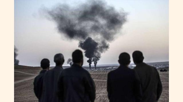 Un grupo de Ciudadanos sirios observa como tres columnas de humo salen de las calles de Kobane.(foto:Diario ABC, S.L.)