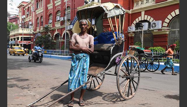 FOTO 2 | India. Mohammad Ashgar, de 65 años, un jalador indio de rickshaw o bicitaxi, posa para una fotografía junto a su herramienta de trabajo en Calcuta el 21 de abril del 2018. Un pilar de las opciones de transporte del siglo XIX, el rickshaw tirado a mano sobrevive en India solo en Calcuta después de haber sido prohibido en otros lugares. El sindicato local de jaladores estima que hay 24,000 personas que se dedican a este oficio en la ciudad, mientras que otras proyecciones más bajas hablan de alrededor de 18,000. El sindicato se ha resistido a todos los intentos previos de prohibir su sustento, organizando previamente protestas masivas de sus miembros contra movimientos para acabar con este oficio. (Foto: AFP)