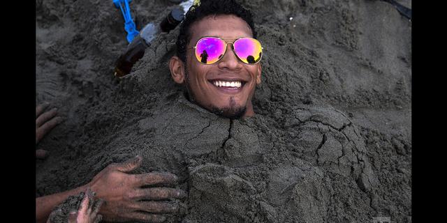 FOTO 5 | En esta imagen, tomada el 16 de febrero de 2020, un hombre sonríe mientras es enterrado por sus amigos en la arena durante una jornada de playa en Agua Dulce, Lima, Perú. (AP Foto/Rodrigo Abd)