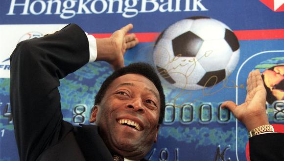 El gran futbolista Pelé hace un gesto para lanzar una pelota de cartón en una conferencia de prensa promocional de la nueva tarjeta Visa de la Copa del Mundo de los bancos de Hong Kong, el 24 de febrero en Hong Kong. (Foto de Robyn BECK / AFP)