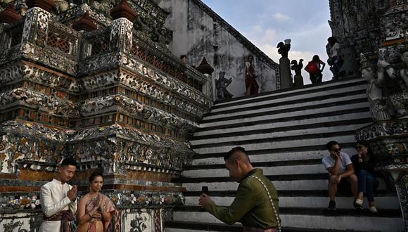 Turistas con trajes tradicionales tailandeses toman fotografías en el templo budista Wat Arun en Bangkok el 9 de diciembre de 2022. (Foto de Lillian SUWANRUMPHA / AFP)