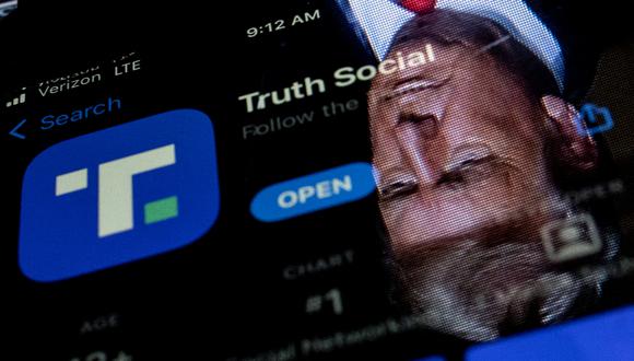En esta ilustración fotográfica de archivo tomada el 21 de febrero de 2022, se muestra una imagen del expresidente de los Estados Unidos, Donald Trump, reflejada en la pantalla de un teléfono que muestra la aplicación Truth Social, en Washington, DC. (Foto de Stefani Reynolds / AFP)