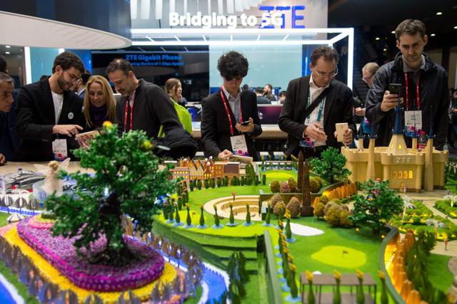 Asistentes toman fotos con el smartphone ZTE Axon7. (Foto: AFP)