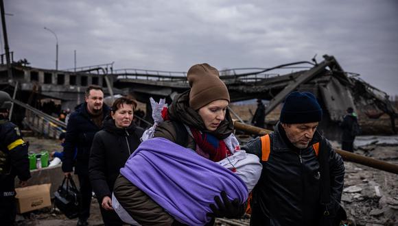 Foto referencial. Una mujer que lleva a su bebé cruza un puente destruido mientras huyen de la ciudad de Irpin, al noroeste de Kiev (Dimitar Dilkoff / AFP)