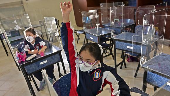 Una estudiante levanta la mano en la Escuela Primaria Motolinia mientras regresan las clases presenciales luego de suspenderse en medio de la pandemia de COVID-19 en la Ciudad de México el 30 de agosto de 2021. (Foto: PEDRO PARDO / AFP).