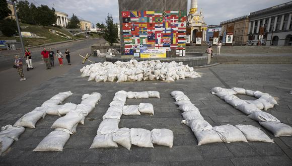 Personas caminan junto a un mensaje que pide ayuda al mundo, escrito con sacos de arenas, en la plaza Maidán, Kiev. (Foto: EFE/ Orlando Barría).