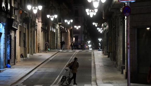 Pocas personas caminan por una calle en medio de un toque de queda establecido para luchar contra la propagación del COVID-19, en Barcelona, el 26 de octubre de 2020. (Josep LAGO / AFP).