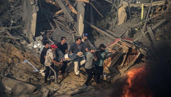 Palestinos transportan a un hombre herido en una camilla lejos de un incendio que arde en una zona destruida tras los ataques aéreos israelíes en la ciudad de Gaza. (Foto de EFE/EPA/MOHAMMED SABER)