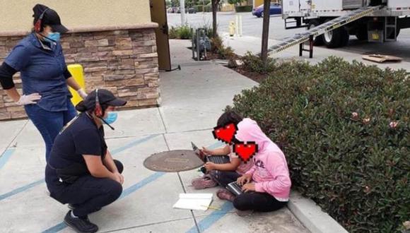 Las niñas se ven sentadas en un andén de concreto con pequeñas laptops en sus piernas, mientras empleados de Taco Bell les hablan.
 (Foto: Twitter)
