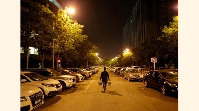 Han Liqun, un gerente de Recursos Humanos de RenRen Credit Management Co., lleva cerveza y comida para sus colegas que lo esperan en la oficina después de la medianoche en Pekín, China. (Foto: Reuters)