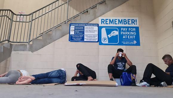 Un grupo de migrantes, en su mayoría provenientes de Venezuela, intentan descansar en un estacionamiento luego de ser liberados por agentes de Aduanas y Protección Fronteriza, en Brownsville, Texas, el 6 de mayo de 2023. (AFP)